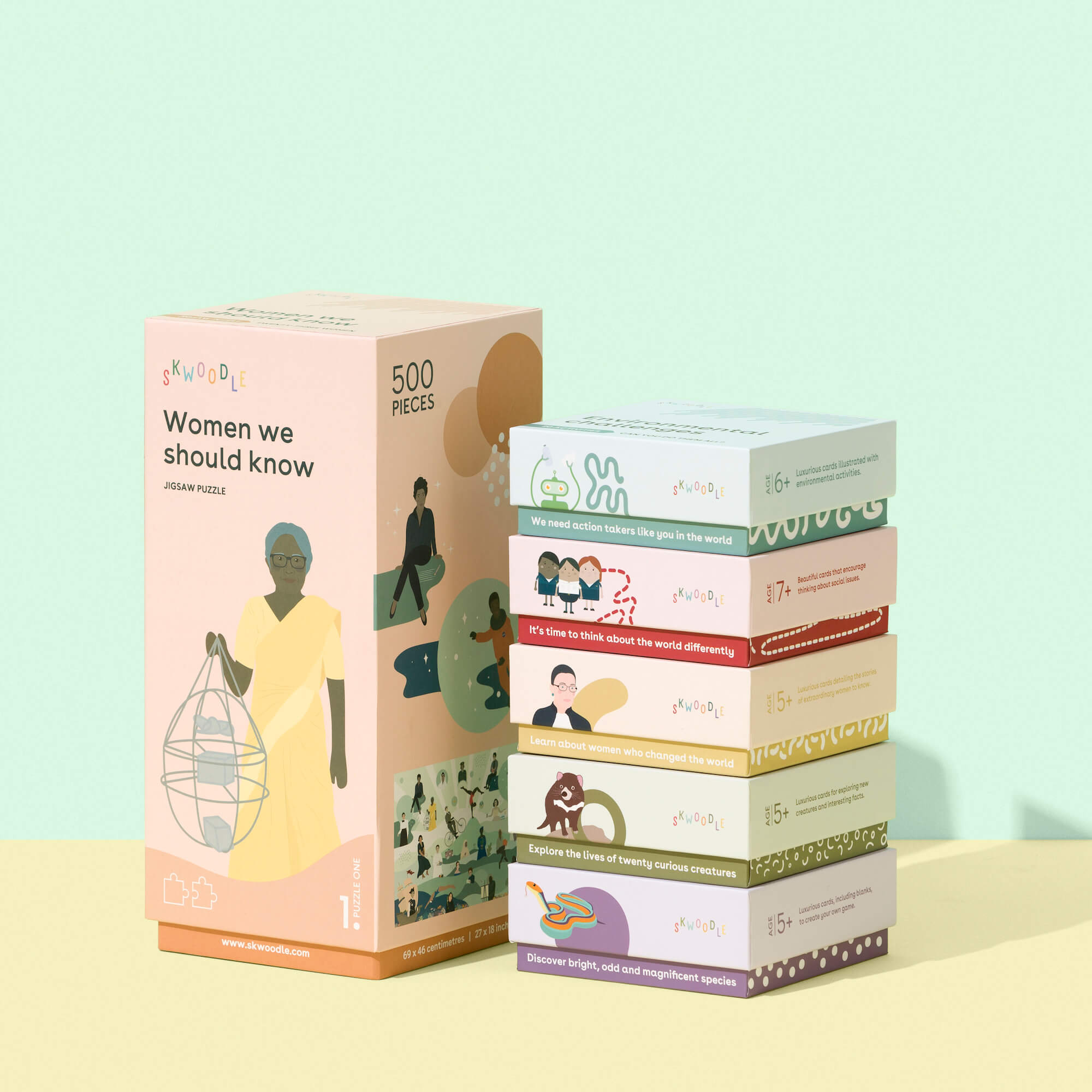 A real photo of the Skwoodle Puzzle box design lined up next to five of the card deck designed boxes
