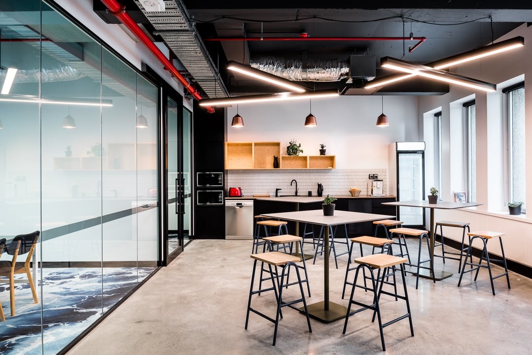 Photo of one of the client projects, this one of the kitchen area with multiple tables and high chairs in the cowork space