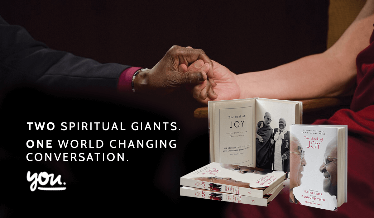An image focused on the hands of Desmond Tutu and the Dalai Lama squeezing each other's hand with a mockup of the book we added and the text two spiritual giants, one world changing conversation, you.