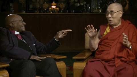 Desmond Tutu pointing his finger at the Dalai Lama who is laughing loudly