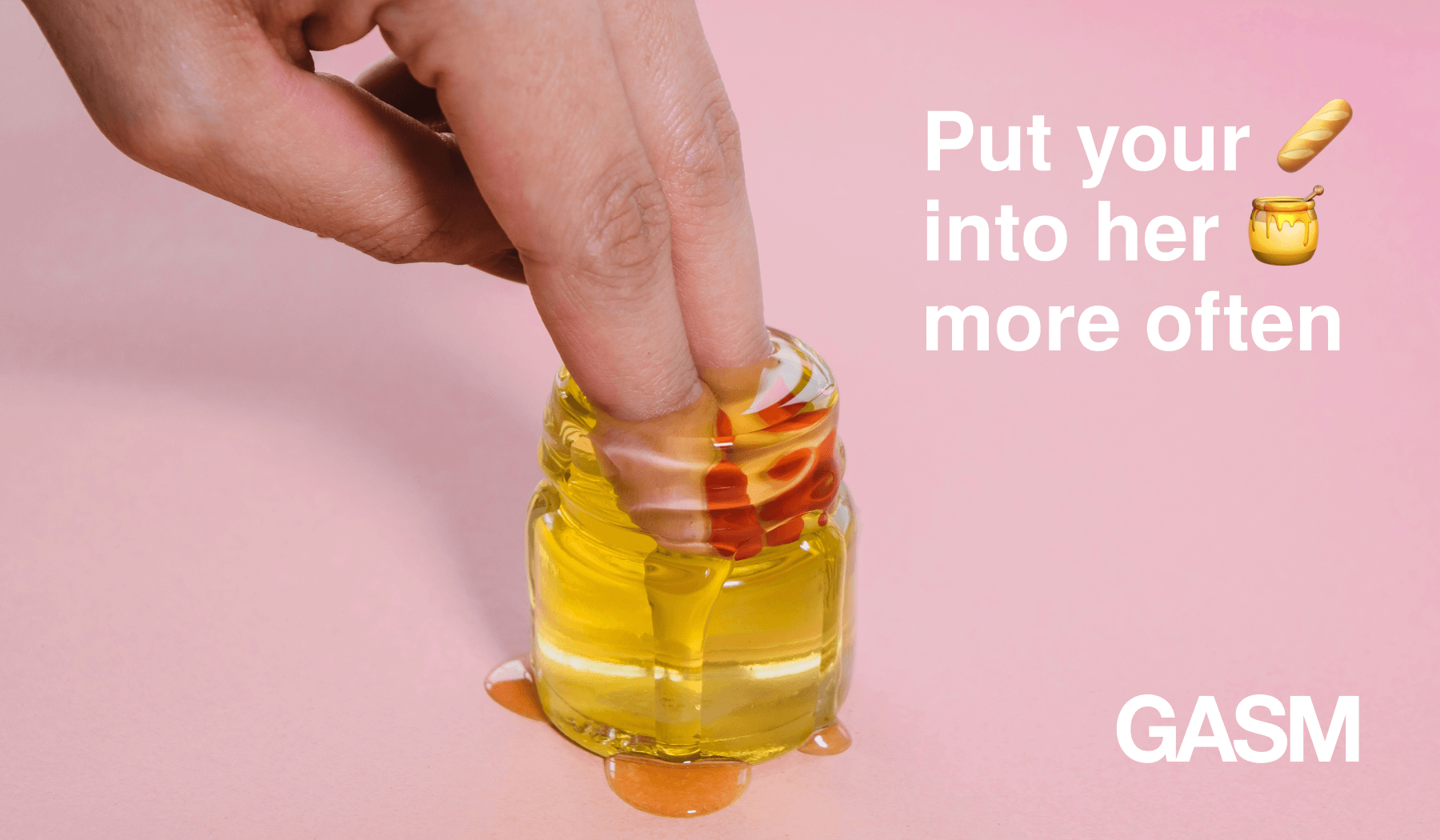 A bright pink background shows a mini jar pot of a honey with the camera focus on the two fingers with red nailpolish dipped into the honey and the text put your (baguette emoji) into her (honey pot emoji) more often. This image is meant for marketing fun only!
