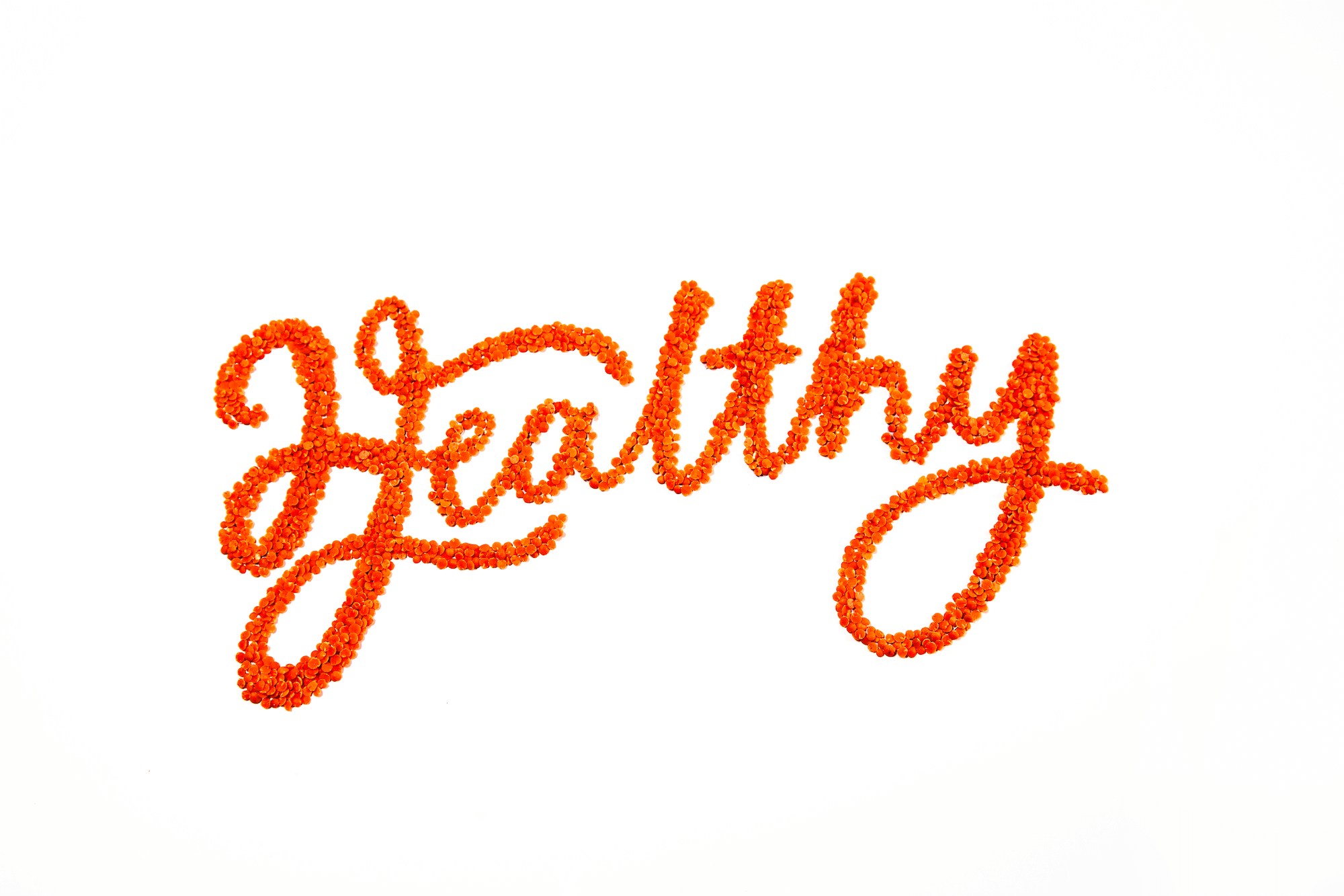 The word Health is shown made from bright orange lentils in cursive form on a white background
