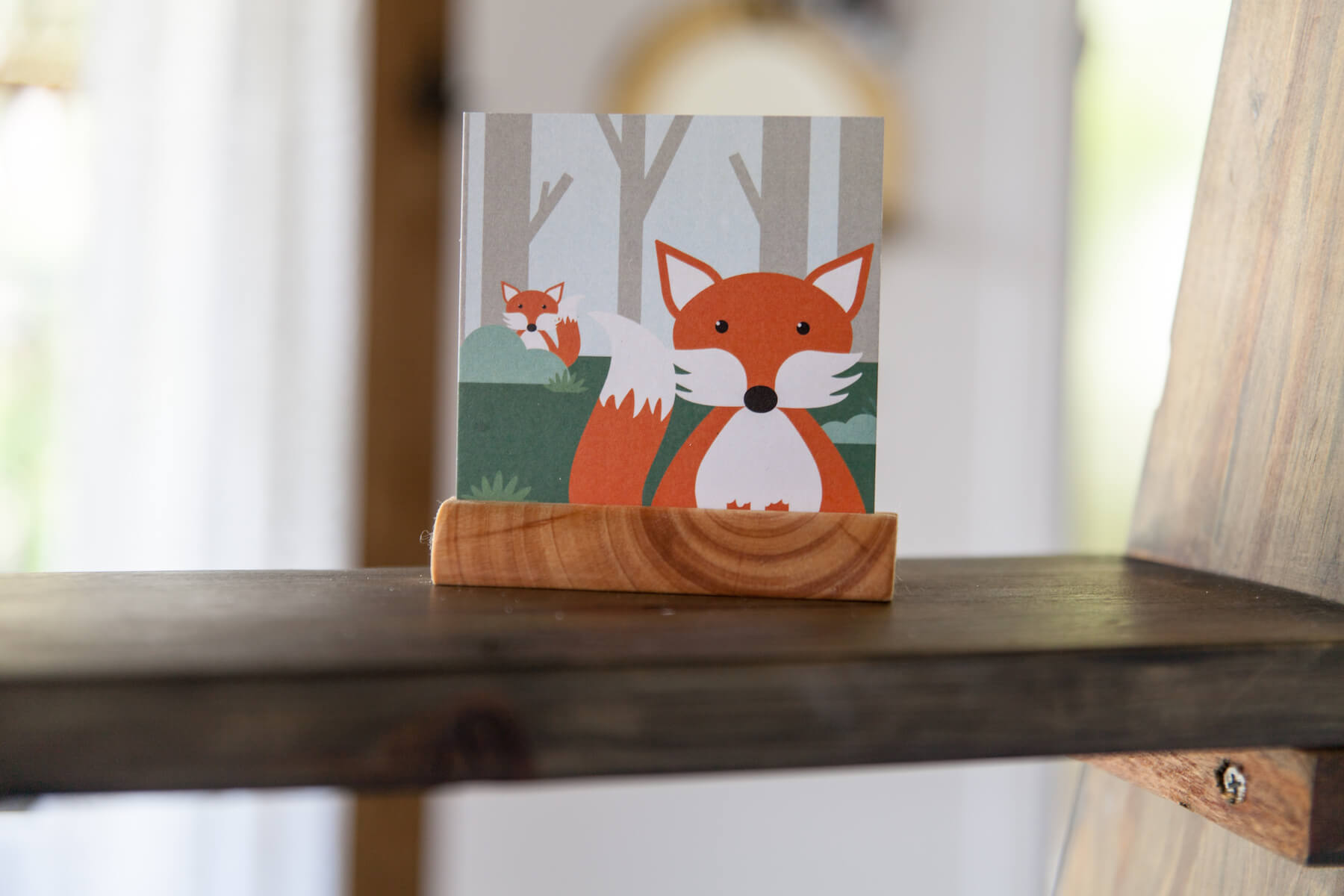 A photo of a wooden round block holder holding one of the animal cards - this time a fox