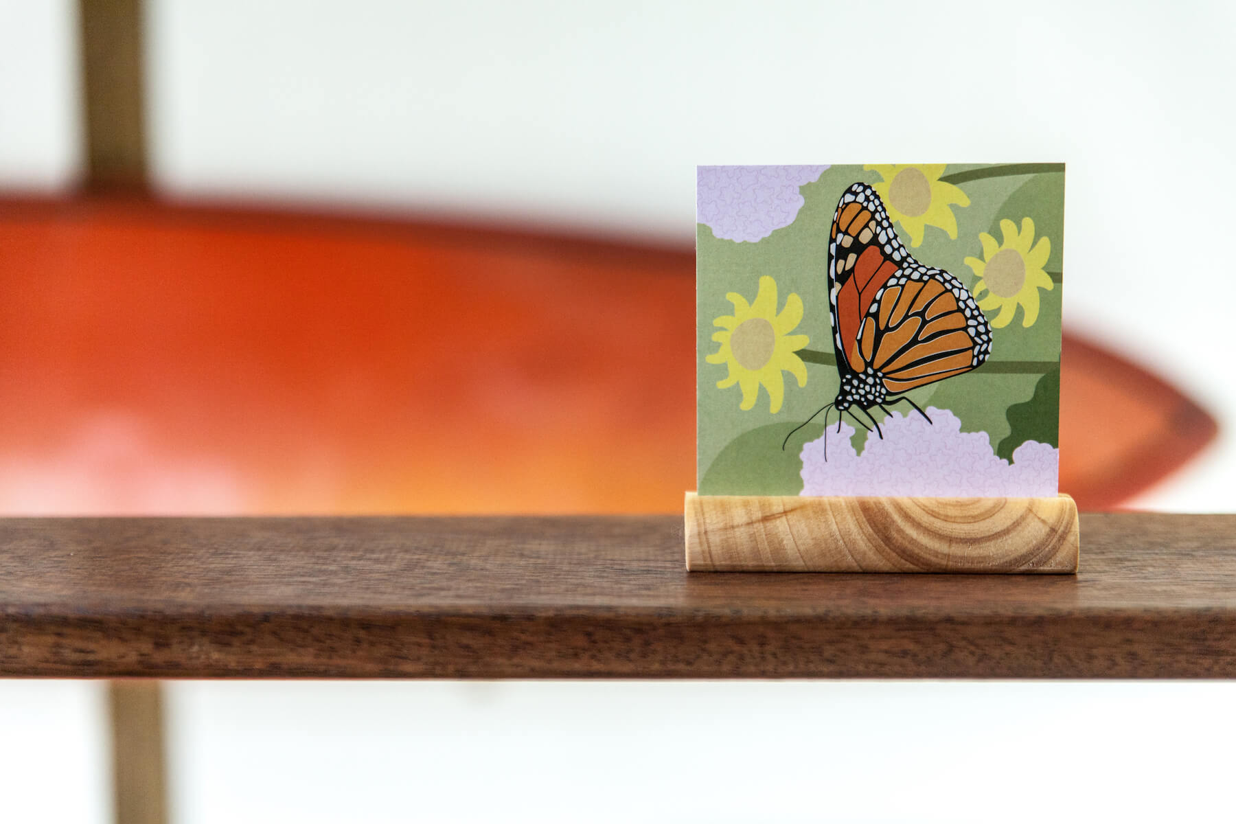 A photo of a wooden round block holder holding one of the animal cards - this time a butterfly